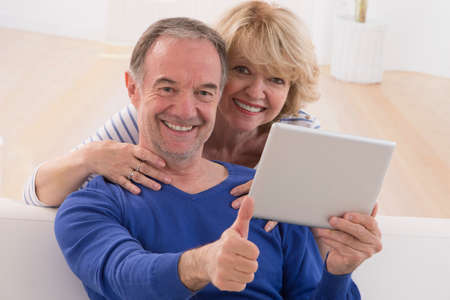 lovely mature couple using tablet computer at homeの写真素材