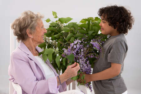 Little boy offering a bouquet of flowers to his grandmotherの写真素材