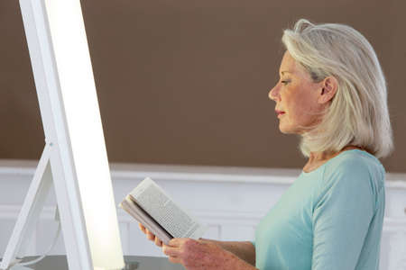 Light therapy-Senior woman getting face phototherapy treatmentの写真素材