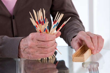 Senior man playing mikado at home or retirement houseの写真素材