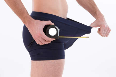close up of man on black boxer underwear measuring penis with a meterの写真素材