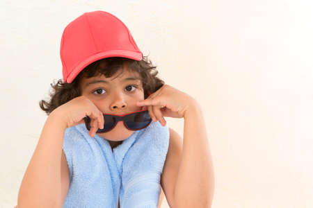 A cute young boy looking over his sunglasses at the camera.の写真素材
