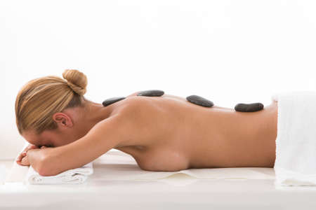 Young woman receiving hot stone massage.の写真素材