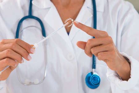 Yound doctor holding an IUD birth control copper coil deviceの写真素材