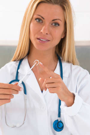 Yound doctor holding an IUD birth control copper coil deviceの写真素材