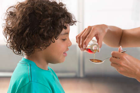 Little boy drinking syrup medicine liquid mother hand feed