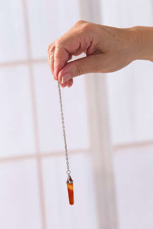 Hand with pendulum tool for dowsing.の写真素材