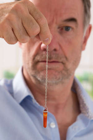 hypnotherapist with his pendulum  during a sessionの写真素材