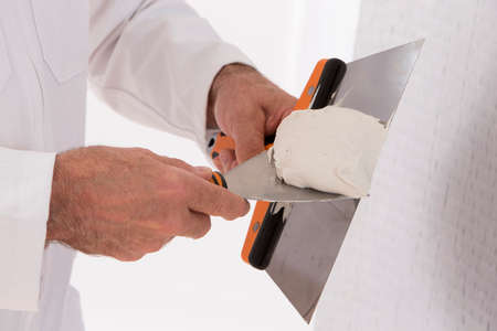 manual worker with wall plastering tools inside a house