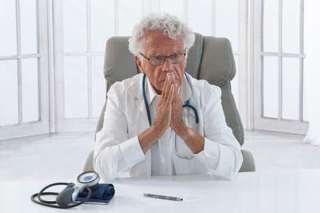 Portrait of an overworked doctor rubbing his head, looking totally stressed out