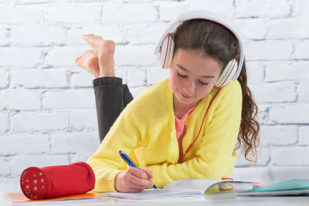 Teen girl listening music  while making homework for schoolの写真素材
