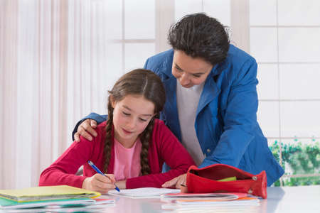 mother assisting her daughter with homework