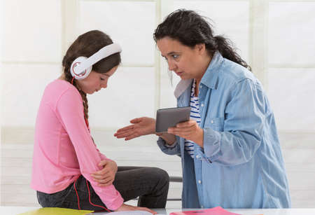 teenager I differently listening to the music in headphones while her mother addressingの写真素材