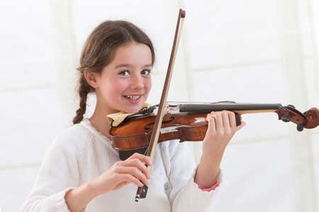 Cute child  playing violin and exercising at homeの写真素材