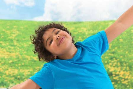 little boy arms outstretched against green meadow