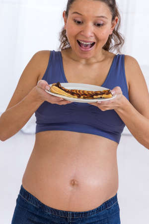 Young Asian pregnant woman   eating sweet cake with envyの写真素材