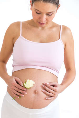 pregnant asian woman with a rose and her hands on her belly