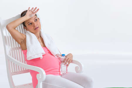 pregnant woman sitting after gym with  a bottle of waterの写真素材