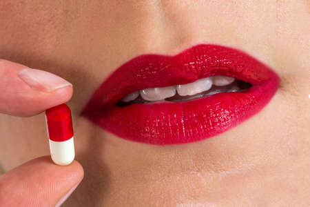Woman's mouth with pill beside