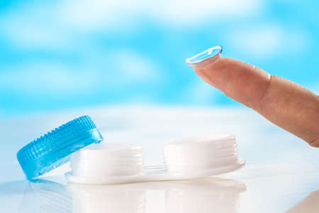 close up Contact lens on finger tipon  blue backgroundの写真素材