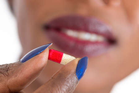 Woman taking pills. Close up of mouth and tabletの写真素材