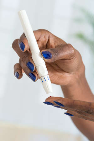 Woman's hands taking diabetes test with glucometerの写真素材