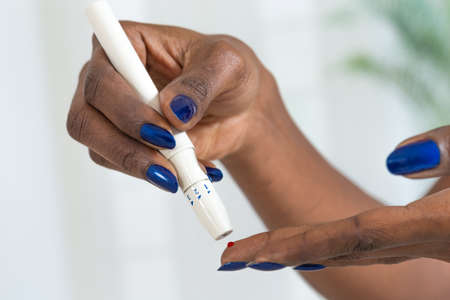 Woman's hands taking diabetes test with glucometerの写真素材