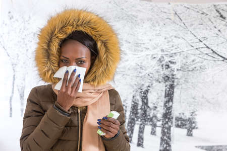 sick african  woman   blowing nose with tissue,  Flu season, vaccineの写真素材