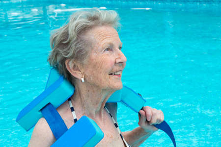 Active senior woman in the pool, doing water sports exercises