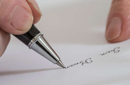 Hand of Woman Writing a letter on white paperの写真素材