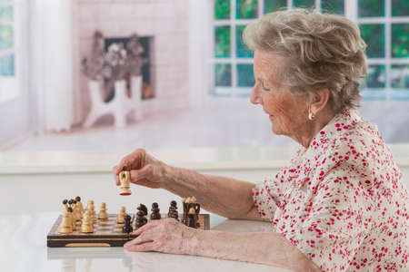 Senior Woman training to play Chess aloneの写真素材