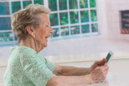 Senior woman browsing on digital tablet at homeの写真素材