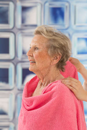 Care giver or nurse givng assistance to elderly woman for shower