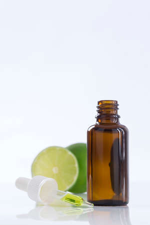 Aromatherapy essential oil bottle with lime fruit and leaf sprig.の写真素材