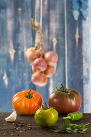 Fresh vegetables on old blue wooden background - tomato, parsley, garlic, pepper, onion, basilの写真素材