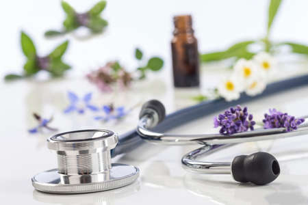 Bottle of essential oil with medicinal plant and stethoscope on whiteの写真素材