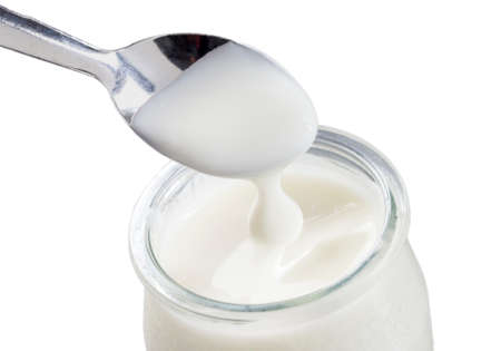 glass pot of yogurt with spoon isolated on white backgroundの写真素材