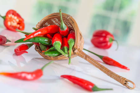 Red chilli peppers in a wicker basket on a kitchen backgroundの写真素材