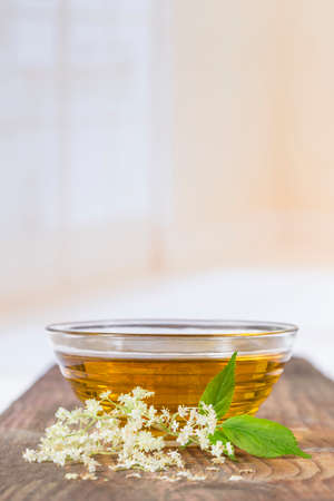 a bowlof elderflower tea with a sprig of fresh flowers and leafsの写真素材