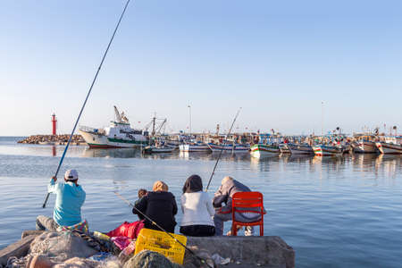 Tusinisian people fishermen catch fish from the shore with the port and fisherman boat on backgroundのeditorial素材