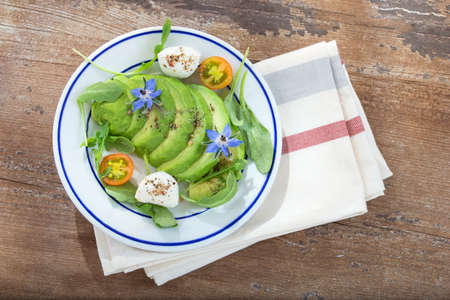 plate of sliced avocado on toast bread with spices and mozzarellaon dishcloth with borage decoration...