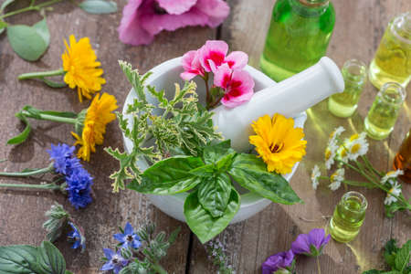 essential oils for aromatherapy treatment with fresh herbs in mortar white backgroundの写真素材