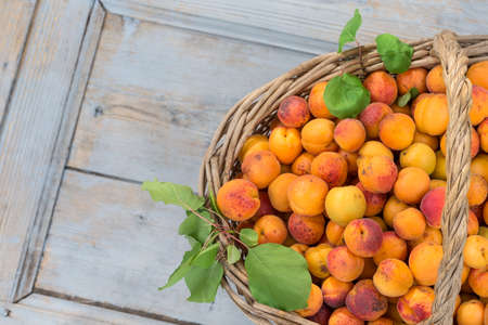 Wicker basket with apricots on a old wooden background Top viewの写真素材