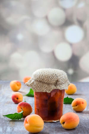Apricot jam in glass jar and fresh fruits, on wooden backgroundの写真素材