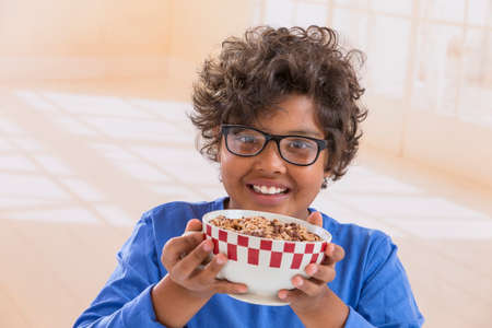 Cute little boy having breakfast at home drinking a large bowl of milk in blue T-shirtの写真素材
