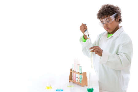 Cute young boy wearing scientist coat doing science experiment with test tube in white