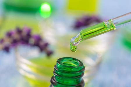 green glass bottles with drops lavender Essential liquid in dropper on wooden background with medicinal flowersの写真素材