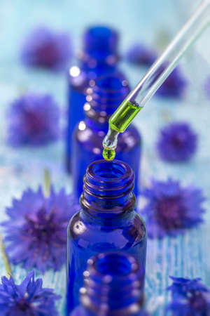 tranparent glass bottles with drops Essential liquid in dropper on wooden background with medicinal flowersの写真素材