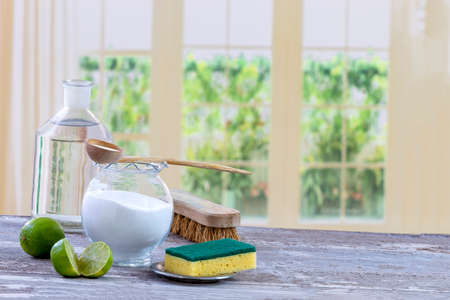 Eco-friendly natural cleaners baking soda, lemon and cloth on wooden table kitchen background,