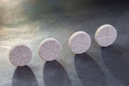 Black and white image of Aligned pils, group of vitamins. Red pills ona gey slate backgroundの写真素材